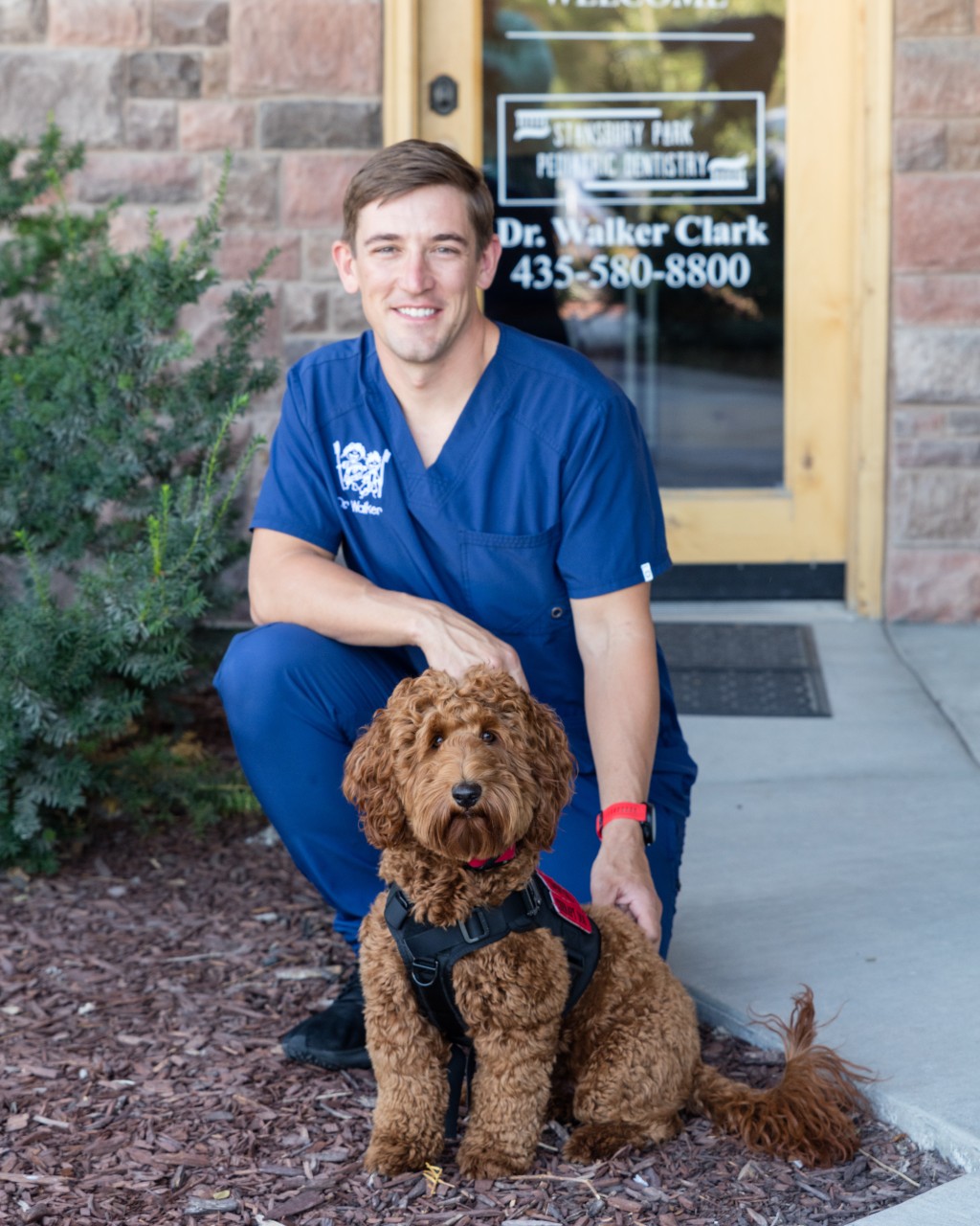 pediatric dentist at door of Stansbury Park with therapy dog